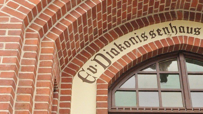 Gotisches Fenster mit Schriftzug „Ev. Diakoniehaus“.